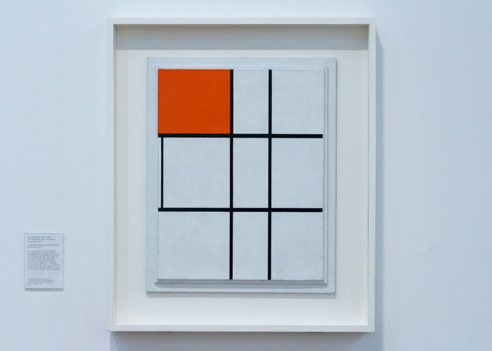 Minimalist geometric art with a bold red square displayed in a gallery.